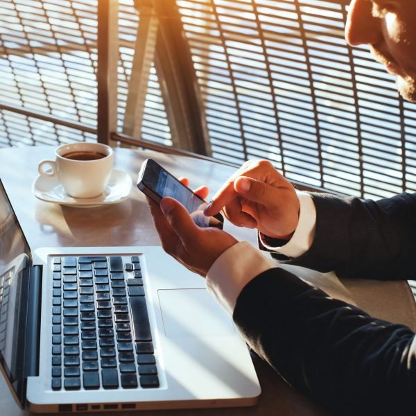 man met telefoon en laptop